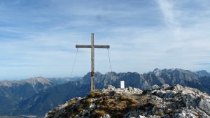 Gipfelkreuz mit Grenzstein. Im Hintergrund das Karwendel.